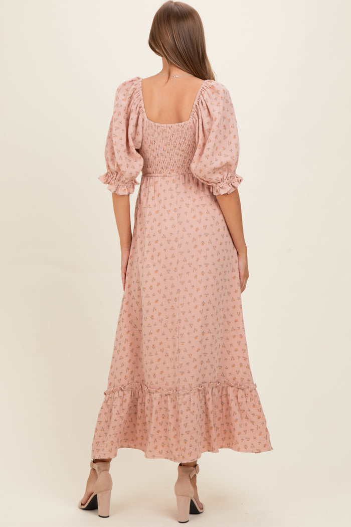 woman wearing a pink floral maternity dress with puff sleeves and a tiered ruffle hem