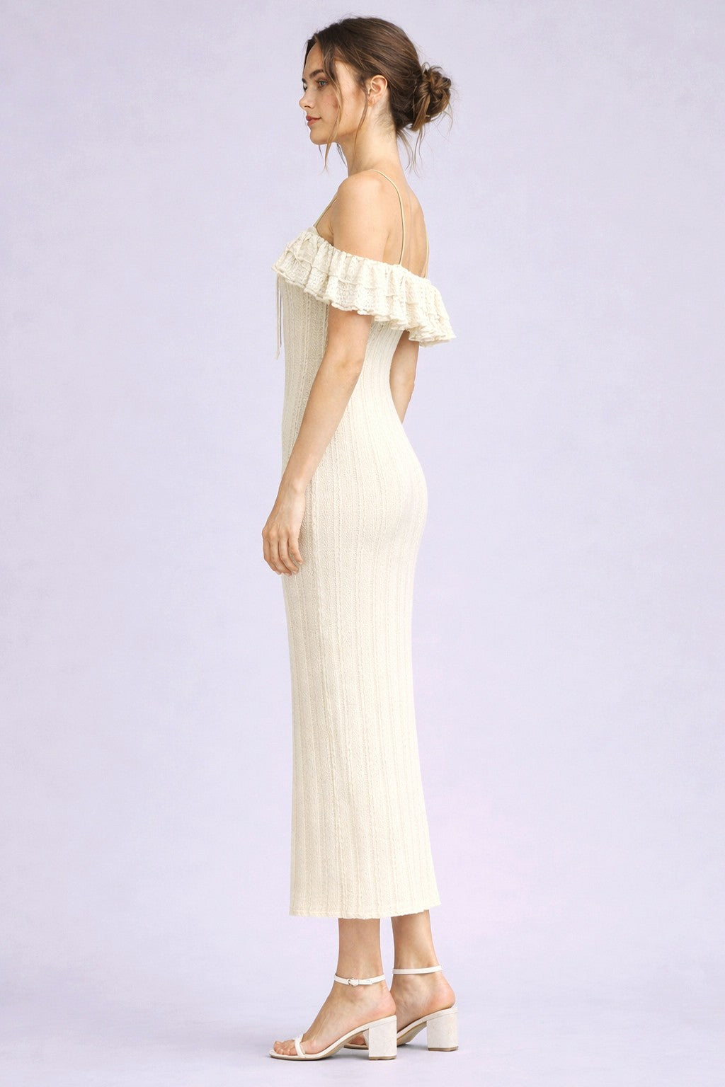woman wearing a cream off-the-shoulder knitted midi dress with a ruffle detail and fitted silhouette