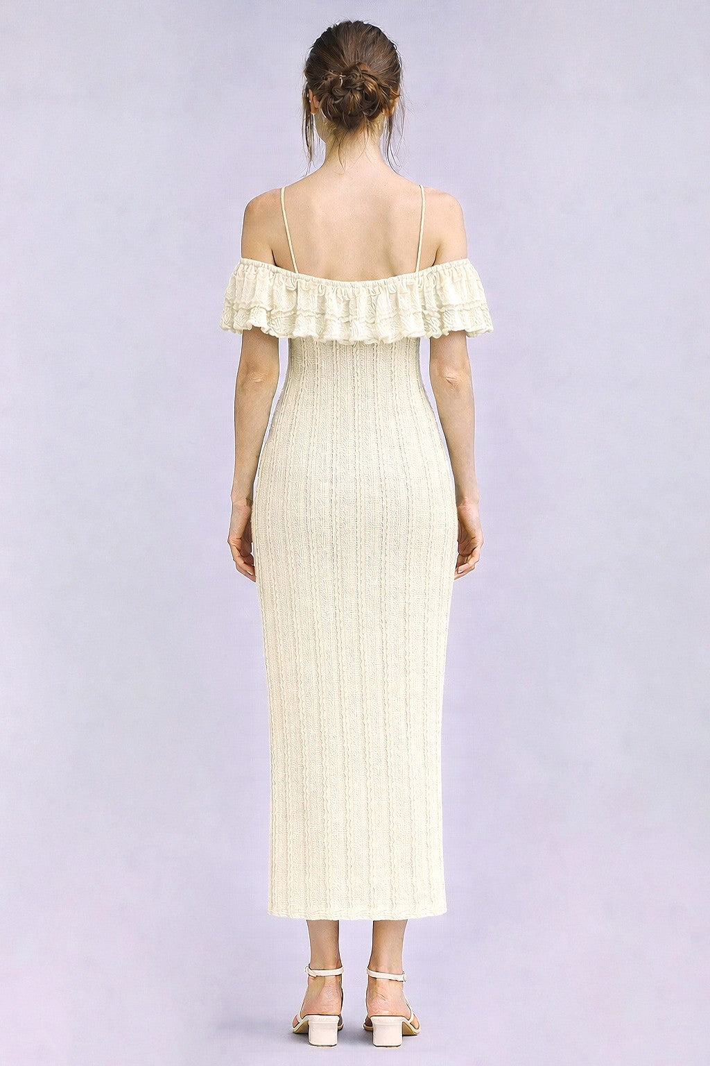 woman wearing a cream-colored off-the-shoulder ribbed maxi dress with ruffle details and a fitted silhouette