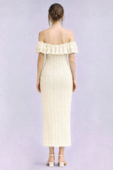 woman wearing a cream-colored off-the-shoulder ribbed maxi dress with ruffle details and a fitted silhouette