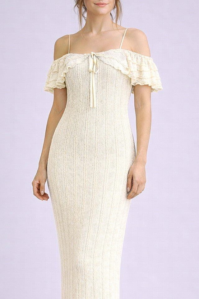 woman wearing a cream off-shoulder knitted dress with ruffled sleeves and a tie detail at the neckline