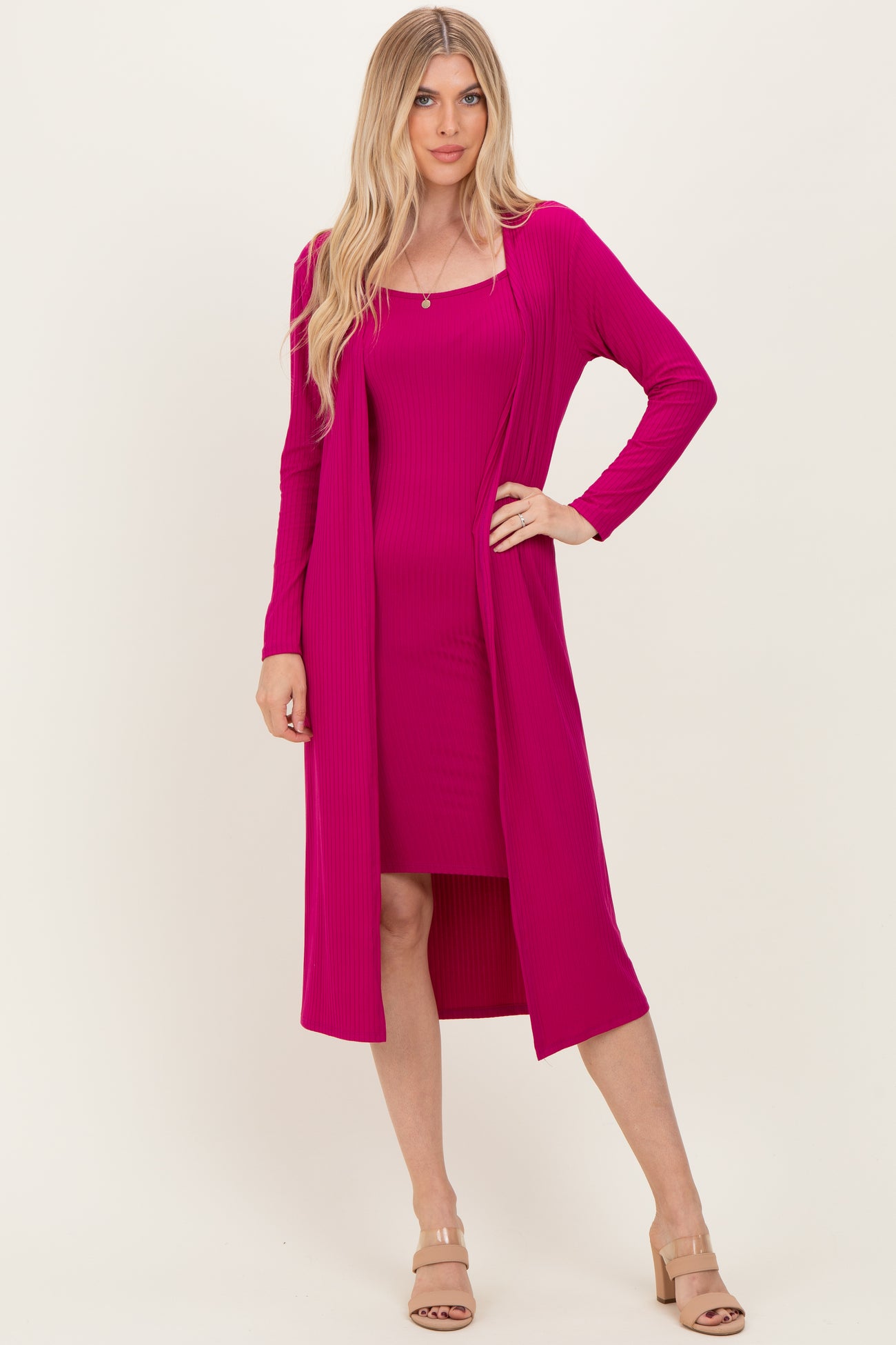woman wearing a hot pink ribbed dress with a matching long cardigan and nude heeled sandals