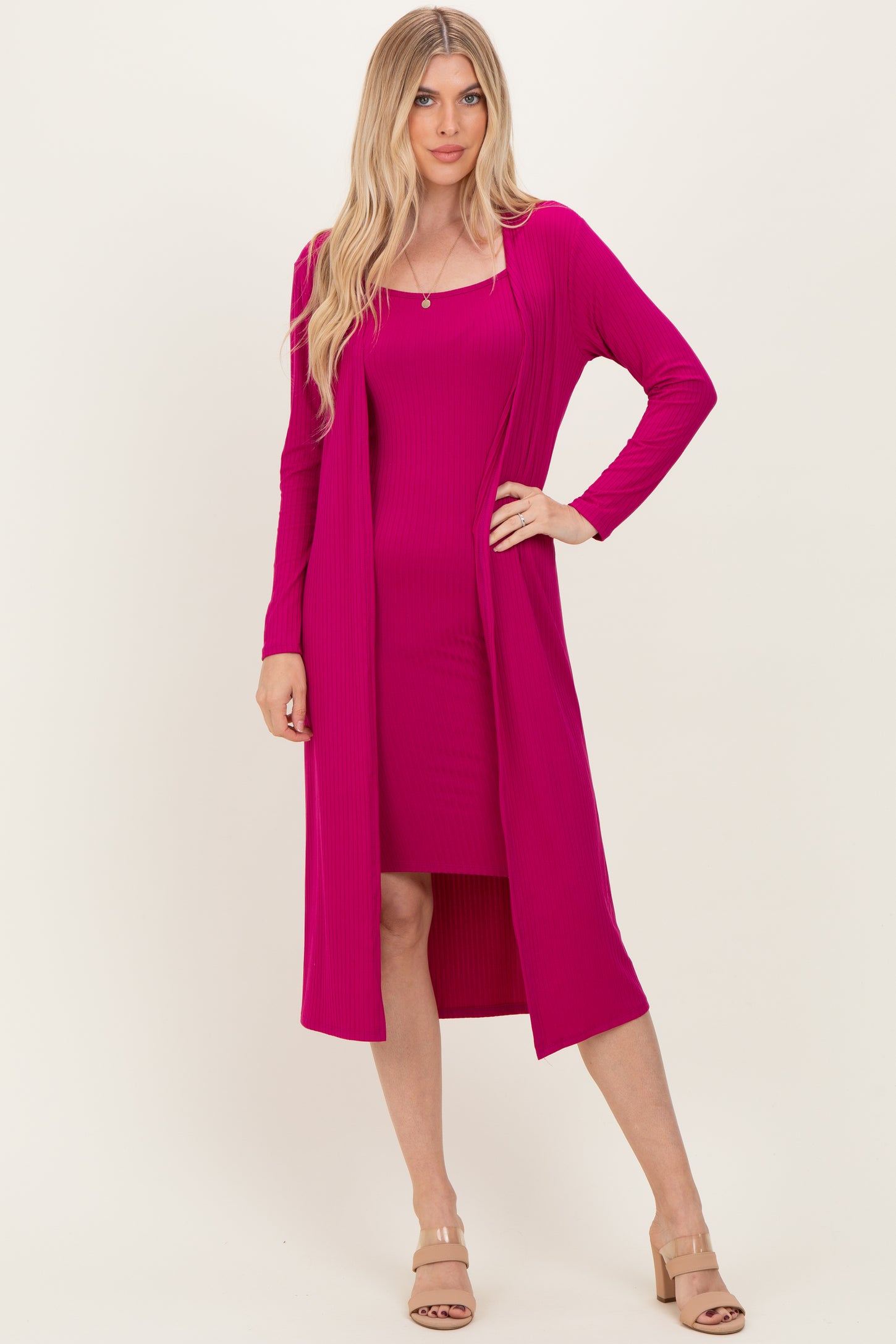 woman wearing a hot pink ribbed dress with a matching long cardigan and nude heeled sandals