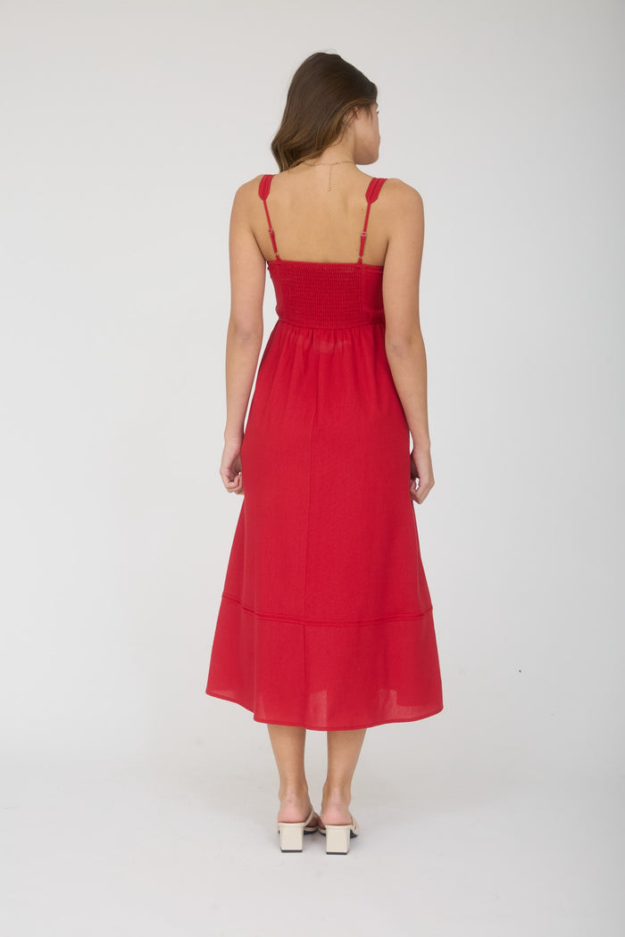 woman wearing a red midi dress with smocked bodice and adjustable straps viewed from the back