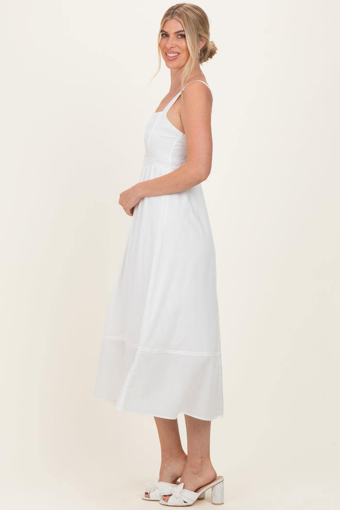 woman wearing a white sleeveless midi dress with a fitted bodice and flowing skirt, styled with open-toe sandals