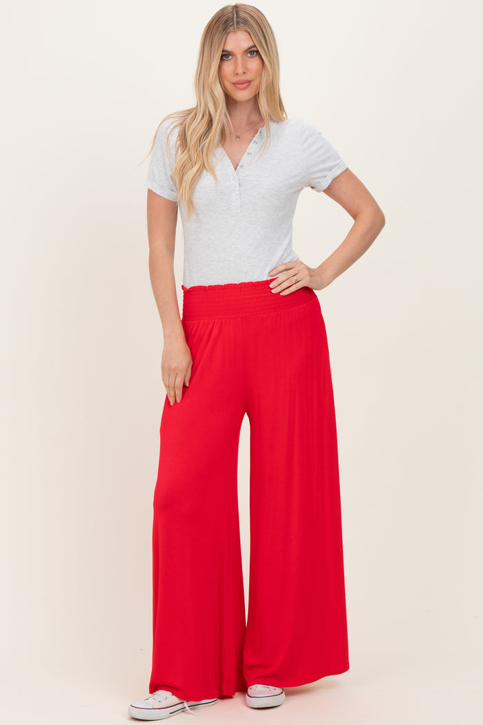 woman wearing a light grey short sleeve henley top and red wide leg pants with an elastic waistband