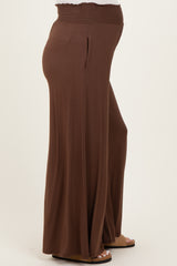 woman wearing brown maternity wide-leg pants with a smocked waistband and side pockets, showing a visible baby bump