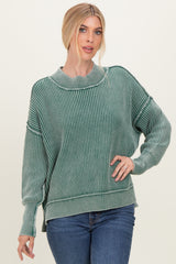 woman wearing a green striped oversized sweater with a high neckline and long sleeves, paired with blue jeans