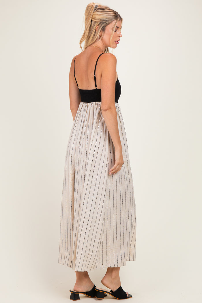 woman wearing a black and white striped maxi dress with a smocked bodice and flowy skirt