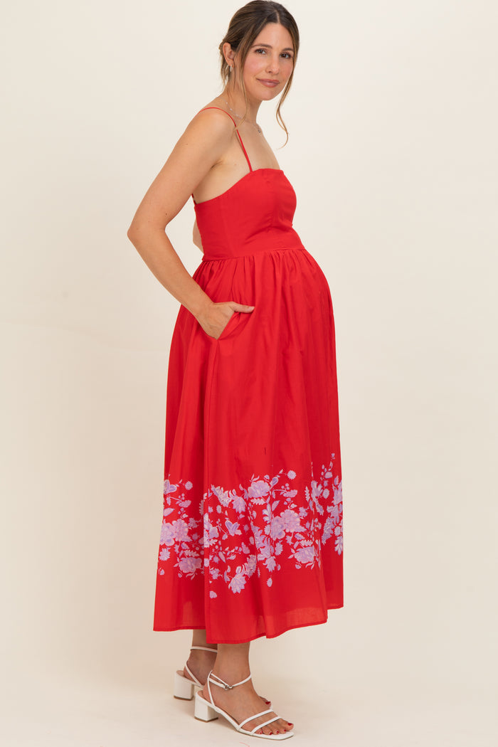 woman wearing a red maternity dress with floral print and pockets, showing her baby bump
