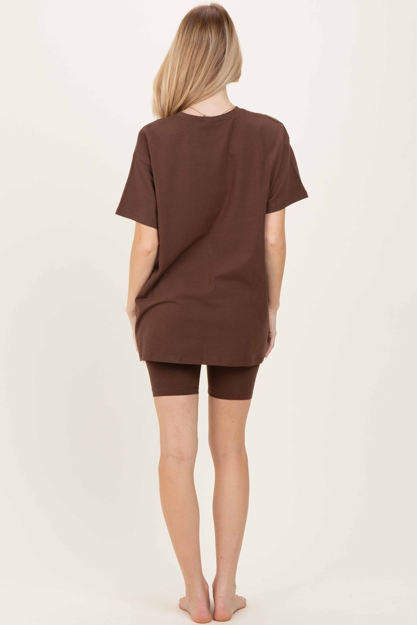 woman wearing a loose brown oversized t-shirt and matching brown shorts, viewed from the back