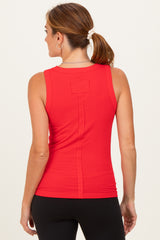 woman wearing a red sleeveless top with a fitted style and a unique back design, paired with black leggings