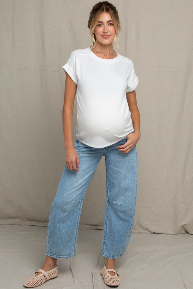 woman wearing a white maternity t-shirt and light blue wide-leg jeans, showing her baby bump