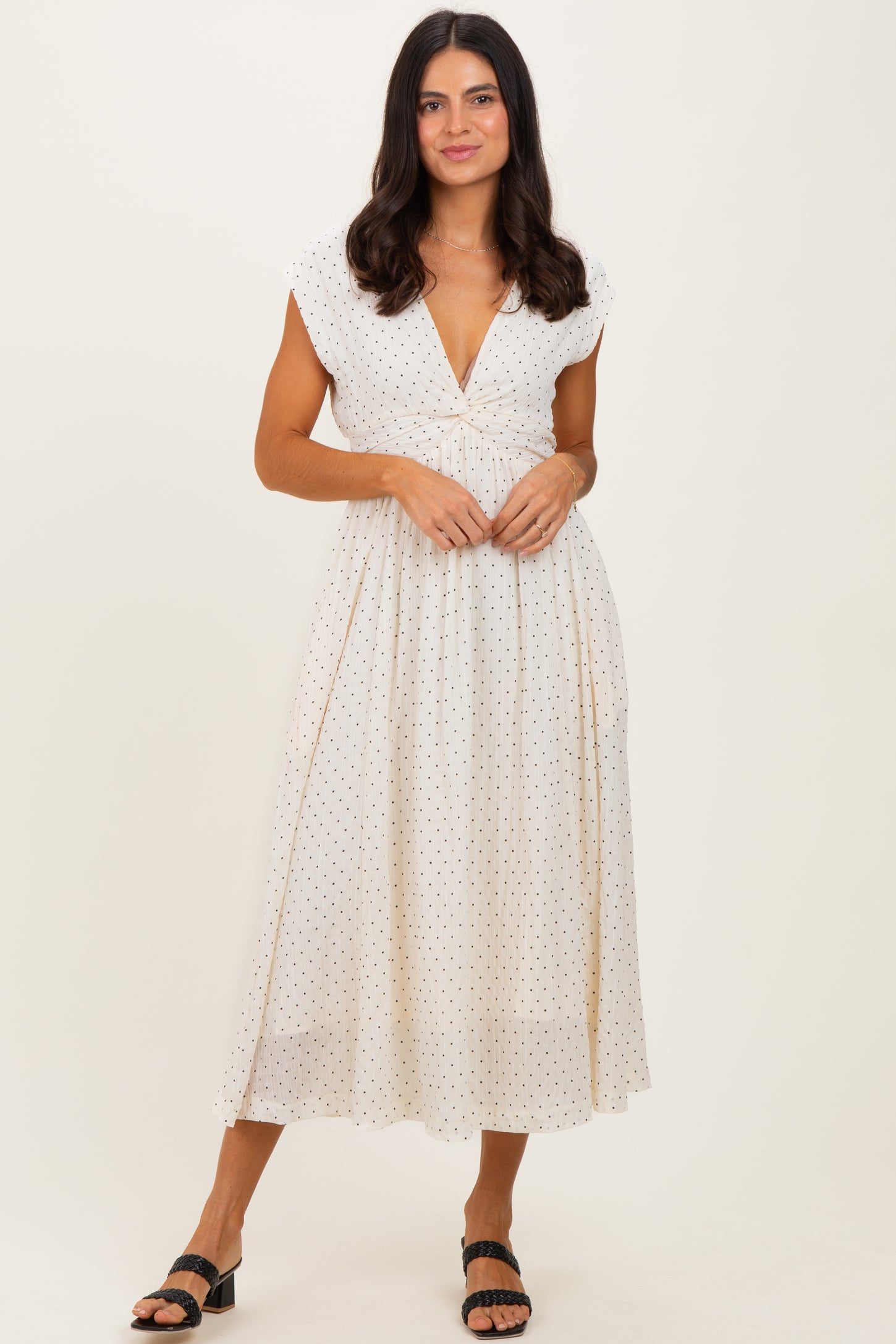 woman wearing a white polka dot midi dress with cap sleeves and a deep v-neckline