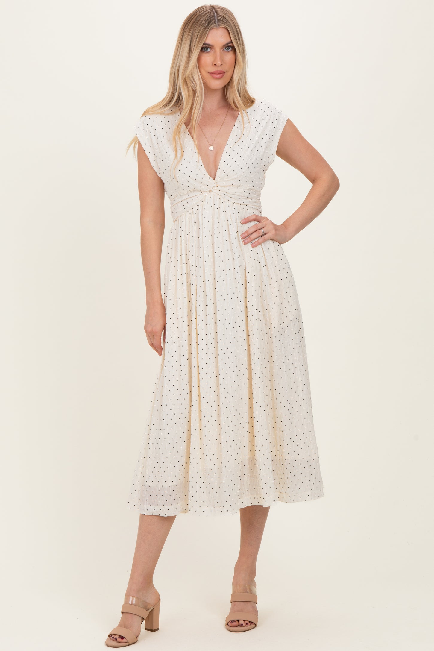 woman wearing a white polka dot midi dress with a deep v-neckline and cap sleeves