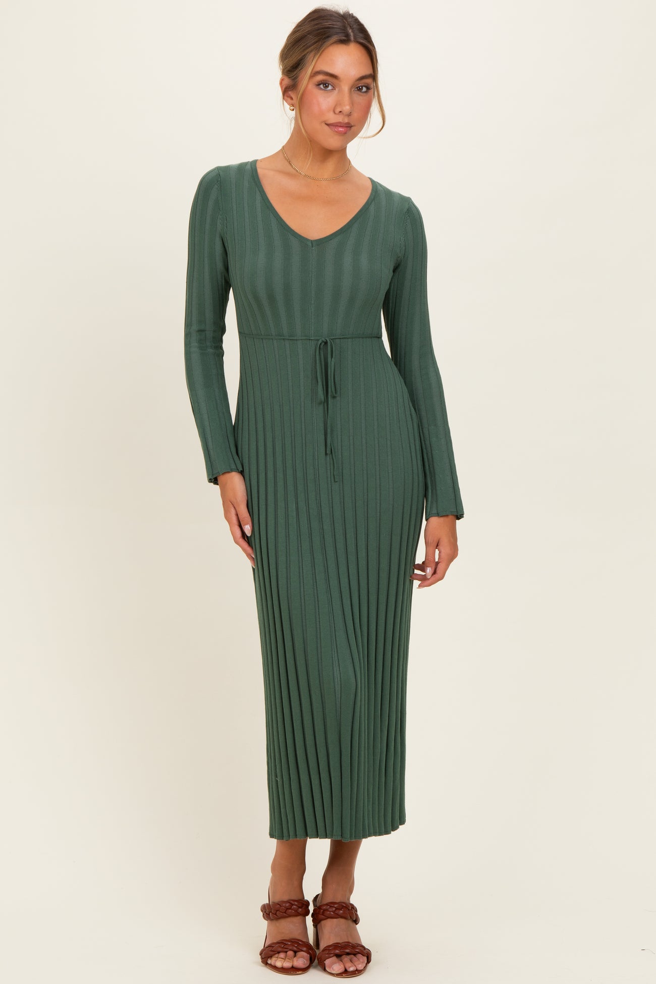 woman wearing a long green ribbed knit maxi dress with a v-neck and belt detail
