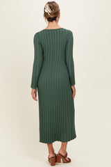 woman wearing a dark green long sleeve ribbed midi dress with a back view showing pleats and a flowy silhouette