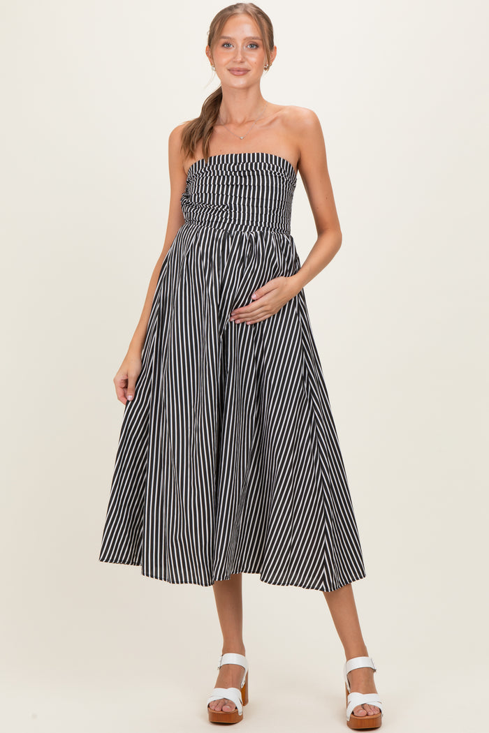 woman wearing a black and white striped strapless maternity dress with a fitted bodice and flowing skirt, showing her baby bump