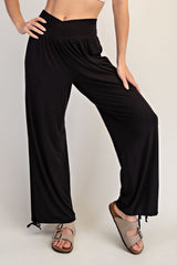 woman wearing black wide-leg pants with a high waistband and drawstring detail, styled with casual sandals