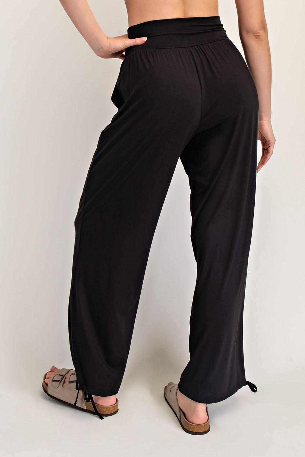 woman wearing black wide-leg pants with a drawstring hem and a relaxed fit, showing the back view