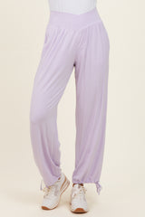 woman wearing lavender casual pants with a high waist and cinched ankle cuffs, paired with white sneakers