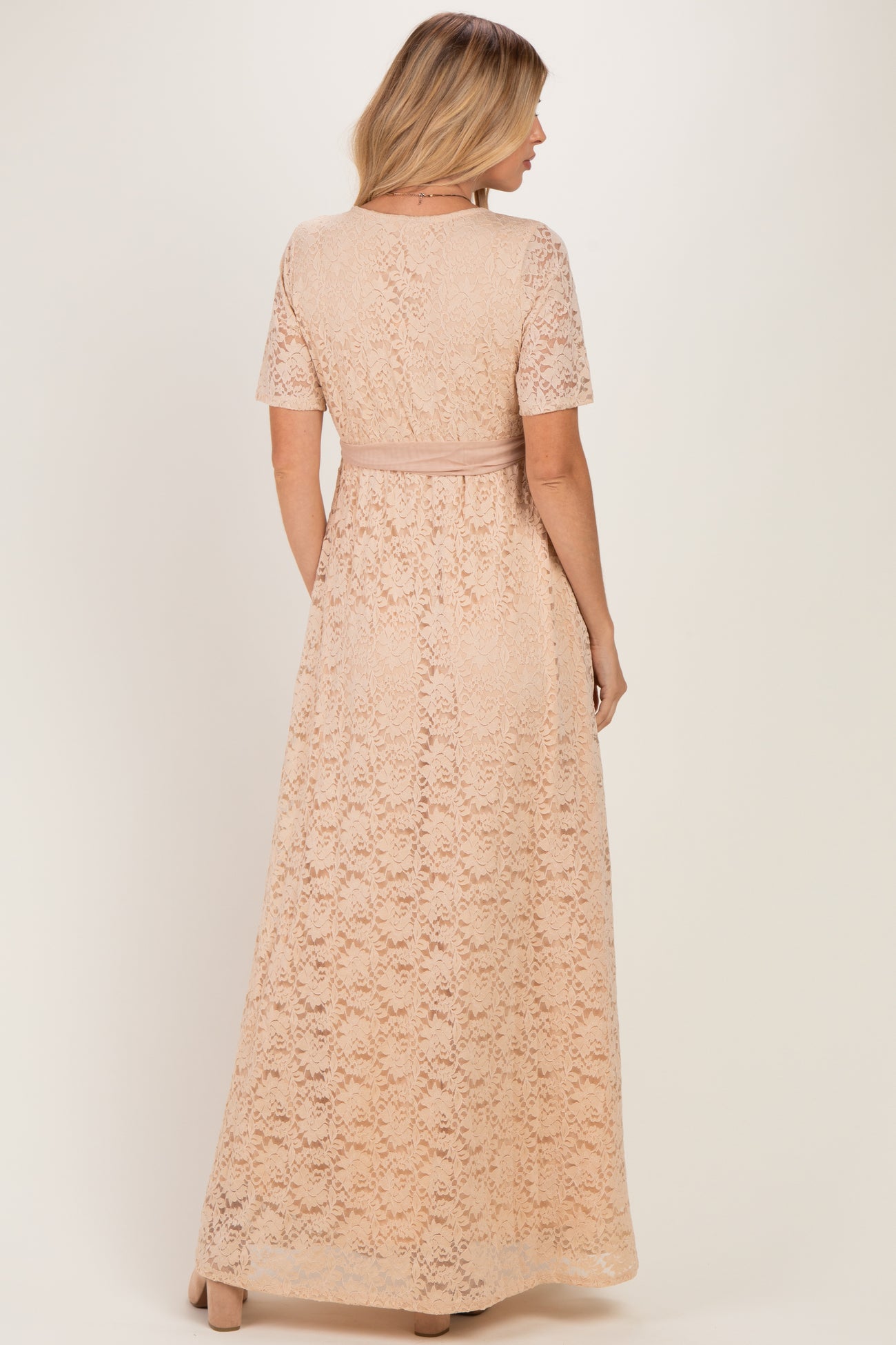 woman wearing a nude lace maxi dress with short sleeves and a waistband, seen from the back
