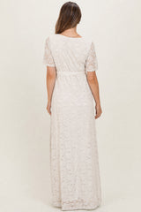 woman wearing a cream lace maternity dress with short sleeves and a tie waist, photographed from the back