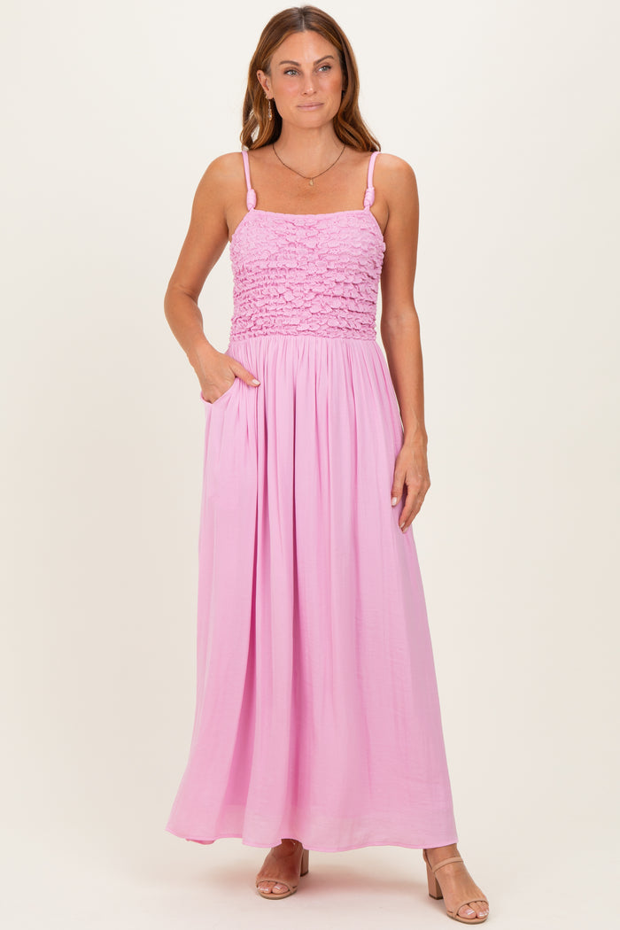 woman wearing a pink smocked maxi dress with adjustable straps and pockets