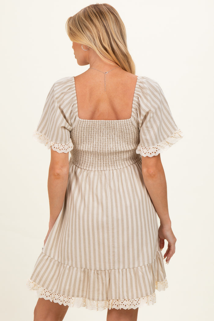 woman wearing a beige striped maternity dress with short sleeves and lace trim, showing the back view