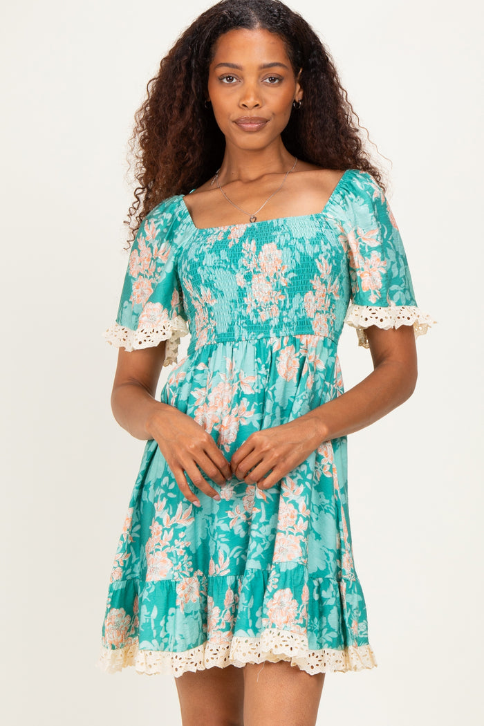woman wearing a teal floral dress with short puff sleeves and lace trim