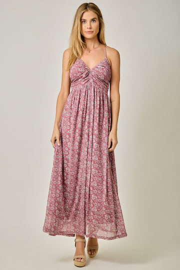 woman wearing a pink floral maxi dress with a twisted knot detail at the bust and spaghetti straps