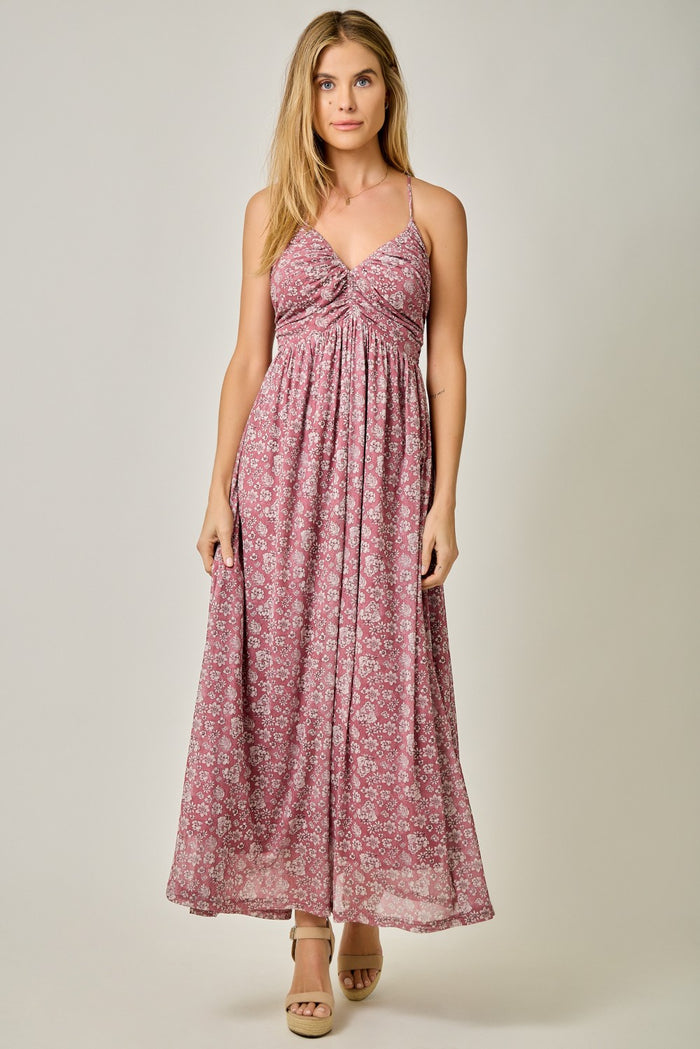 woman wearing a pink floral maxi dress with a twisted knot detail at the bust and spaghetti straps