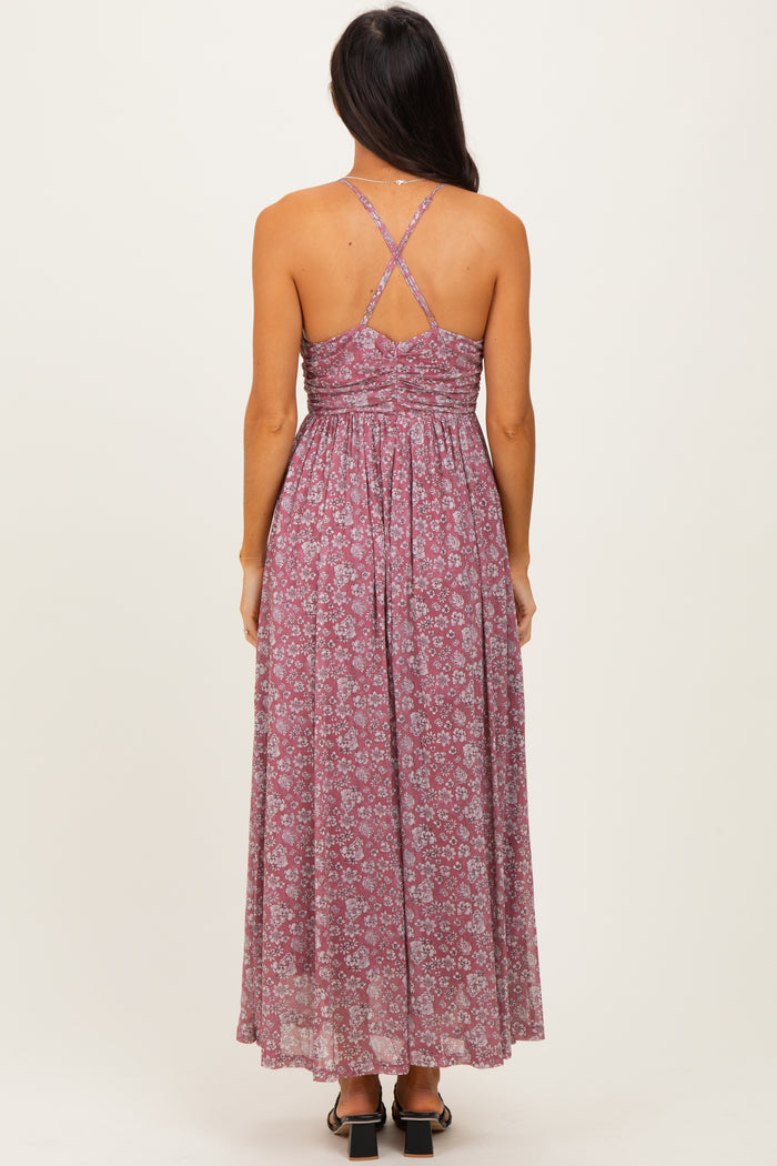woman wearing a back view of a long floral maxi dress with crisscross straps in shades of pink and mauve