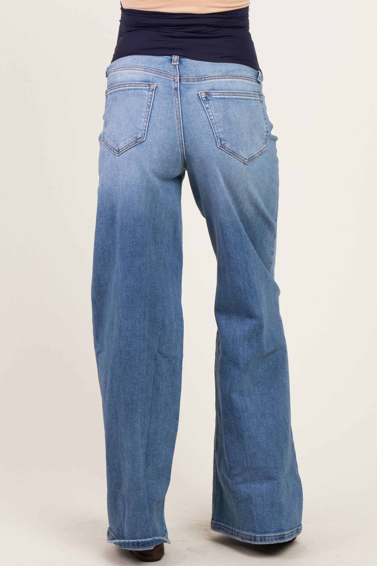 woman wearing light blue maternity wide-leg jeans, showcasing the back view with a stretchy waist panel