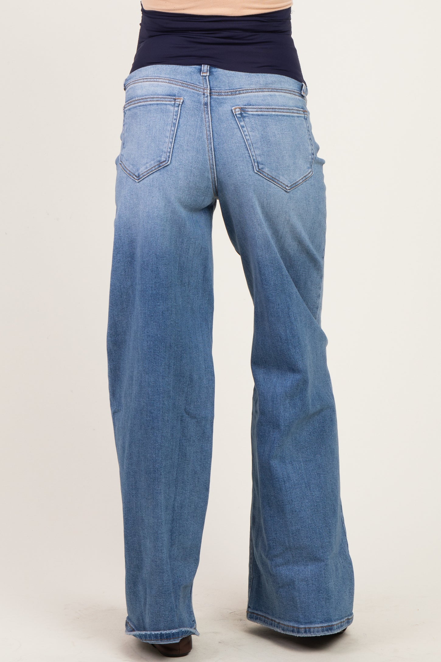 woman wearing light blue maternity wide-leg jeans, showcasing the back view with a stretchy waist panel