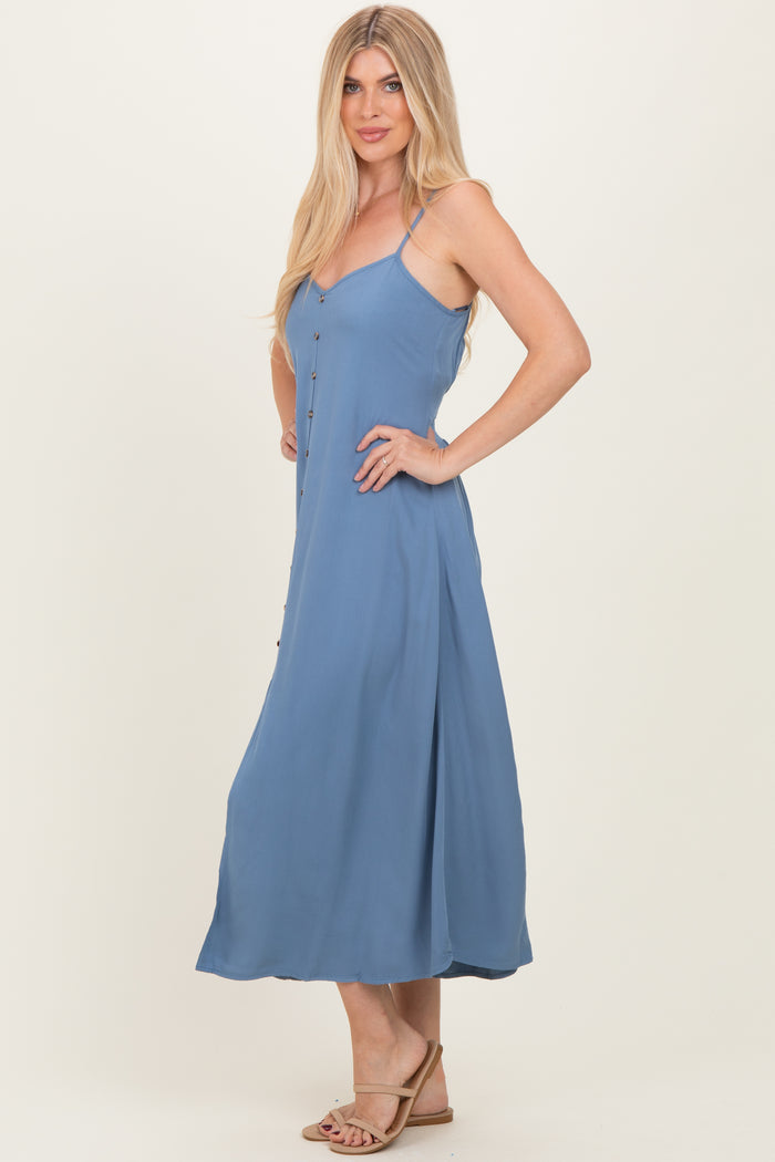 woman wearing a light blue spaghetti strap maxi dress with button details and a flowing skirt