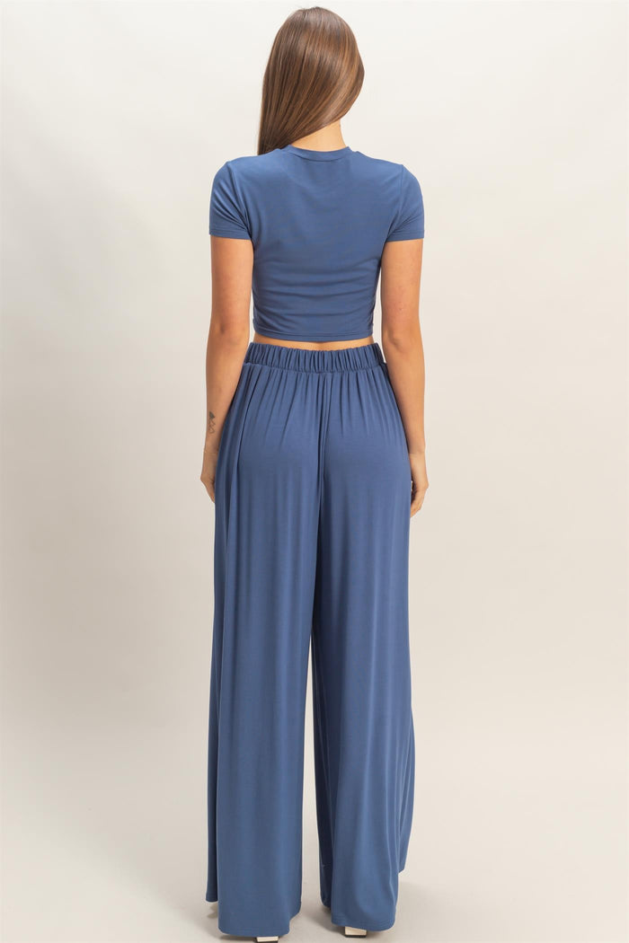 woman wearing a blue cropped t-shirt and matching wide-leg pants, viewed from the back