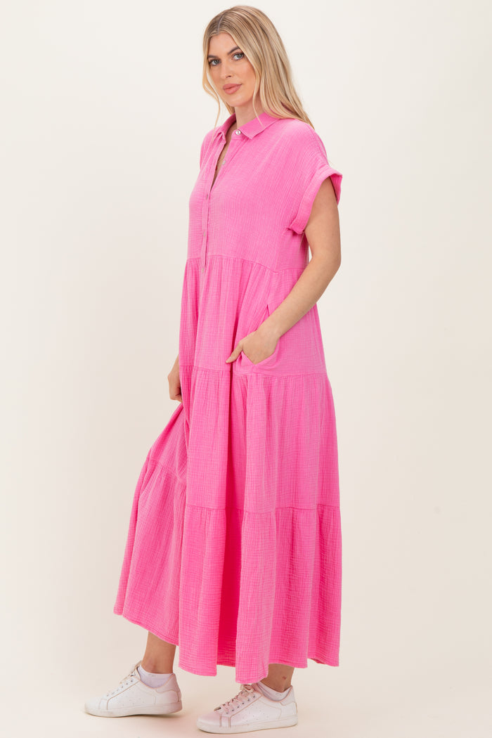 woman wearing a bright pink short sleeve tiered midi dress with pockets and a button-up collar