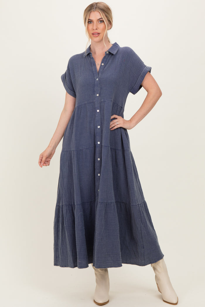 woman wearing a navy blue button-down maxi dress with short sleeves and tiered details, standing against a neutral background
