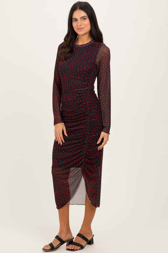 woman wearing a burgundy polka dot long sleeve midi dress with ruching detail and a high slit