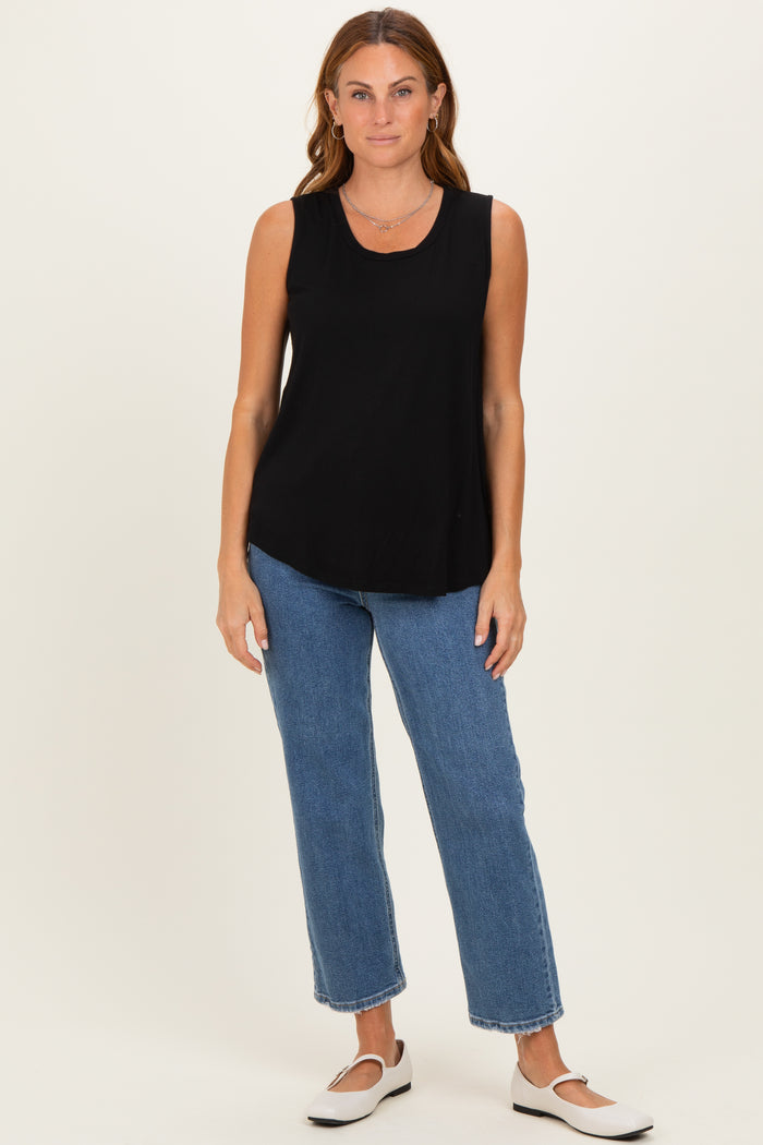woman wearing a black sleeveless top with a rounded hem and blue high-waisted straight leg jeans