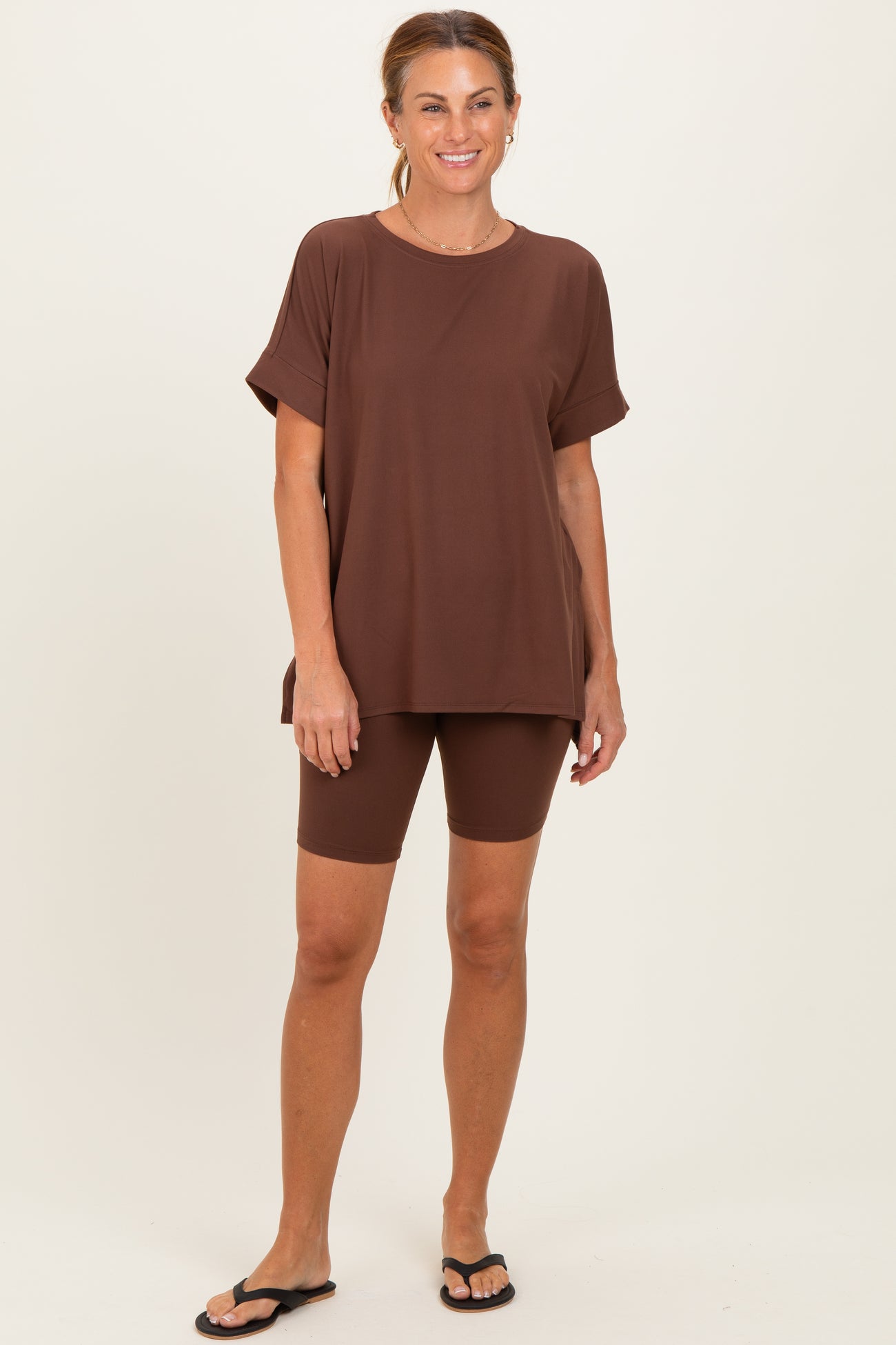 woman wearing a brown oversized t-shirt and matching bike shorts, styled with black flip-flops