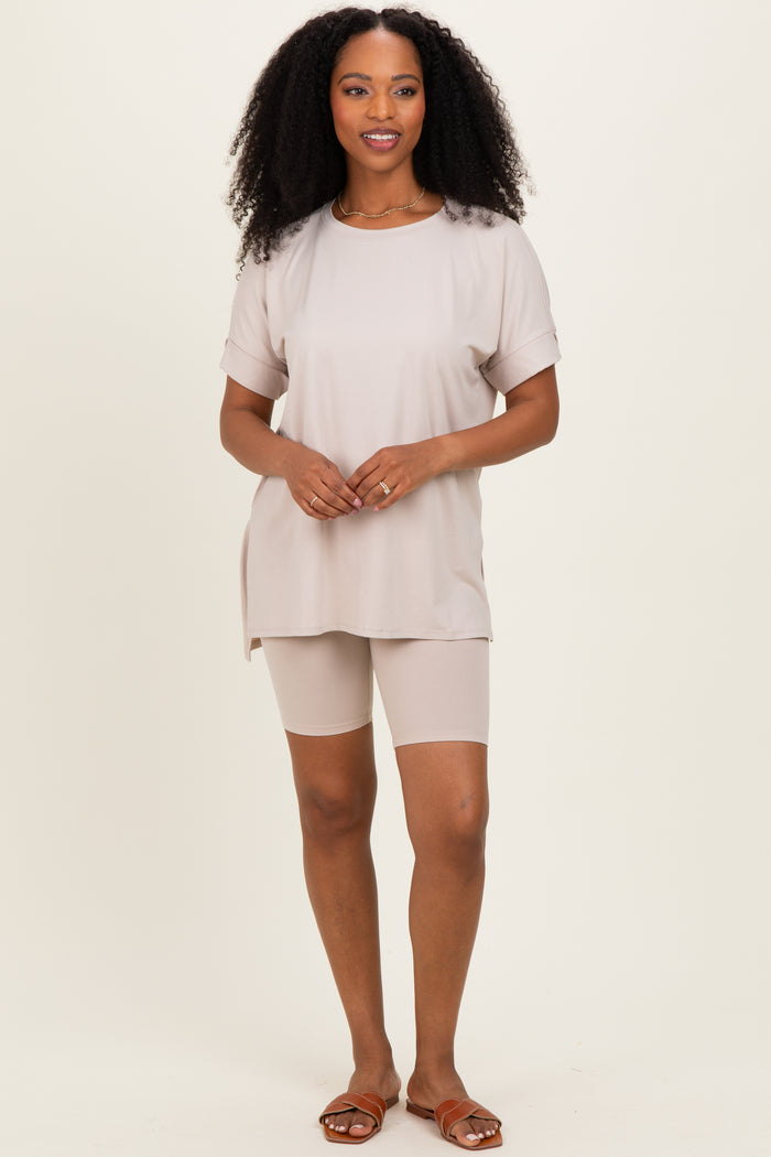 woman wearing a beige oversized t-shirt and matching bike shorts, standing with hands on hips