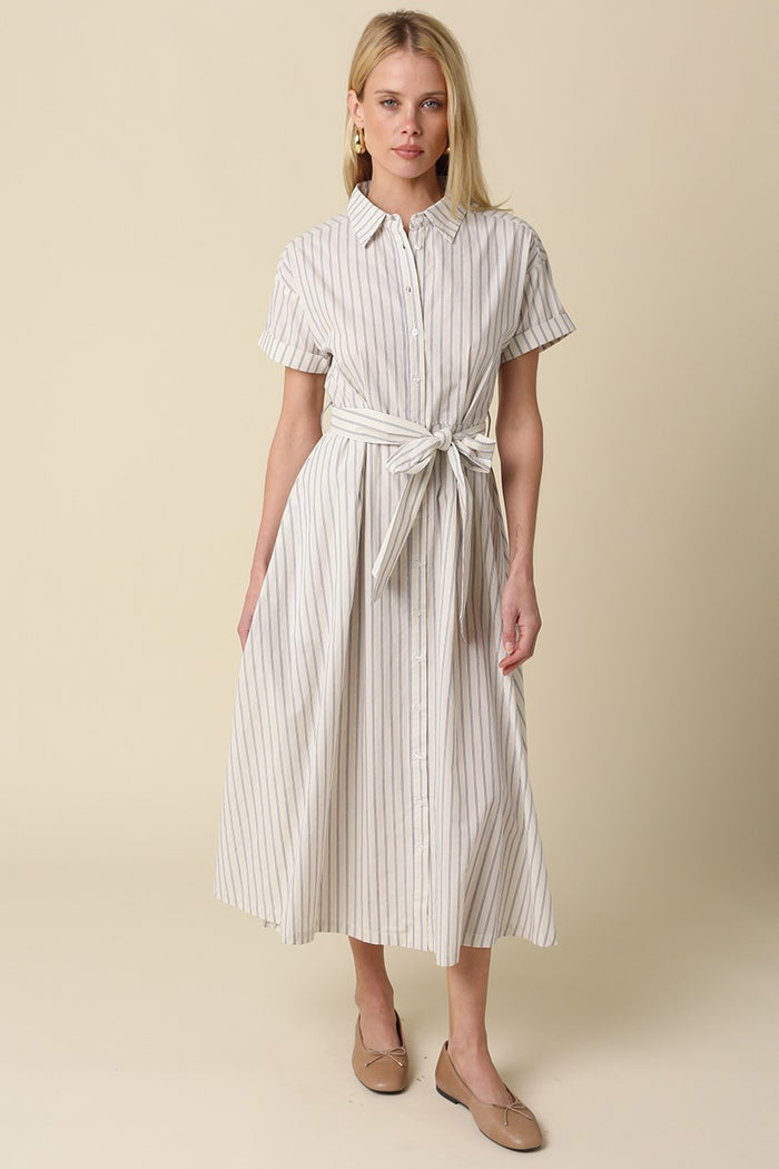 woman wearing a striped midi shirt dress with buttons and a tie waist, styled with flat shoes