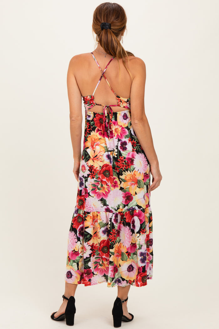 woman wearing a floral maxi dress with a tie back and spaghetti straps, showing a vibrant array of flowers