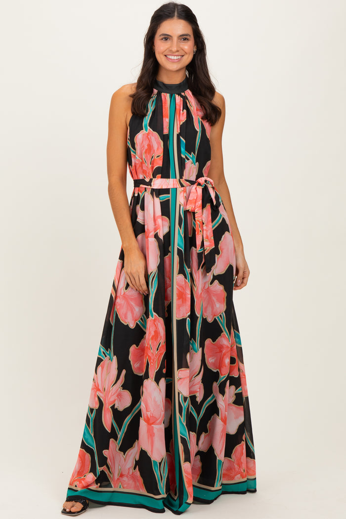 woman wearing a black maxi dress with pink floral print and a halter neckline, featuring a tied waist belt