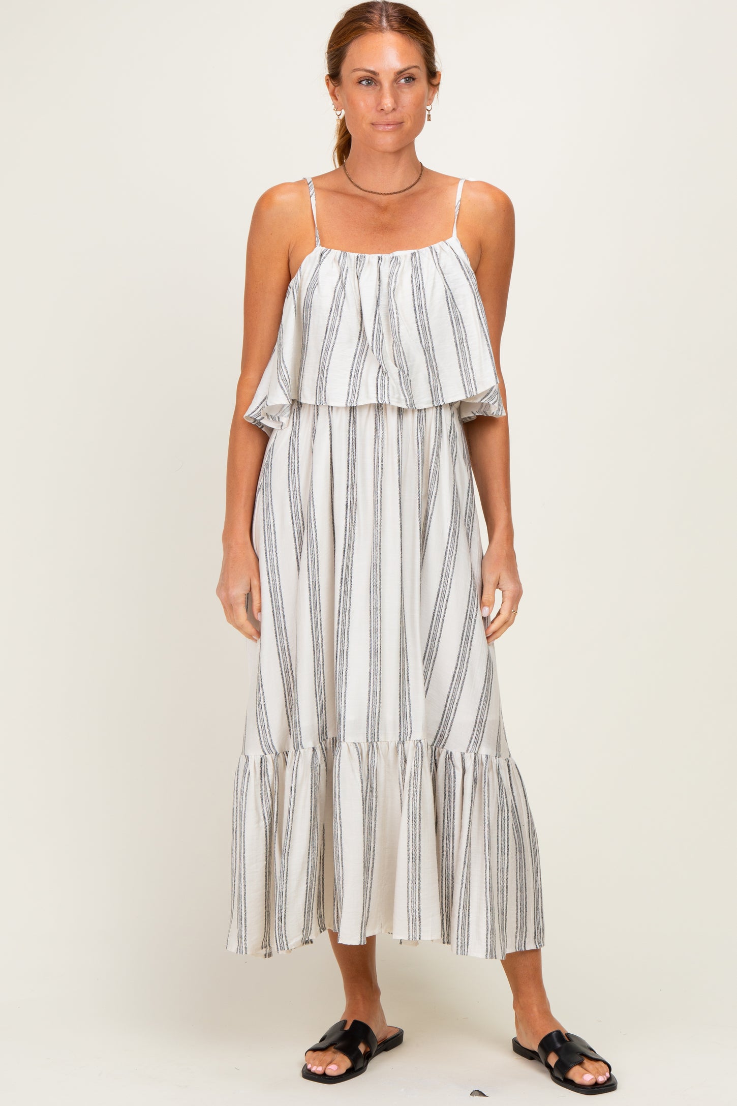 woman wearing a cream and black striped maxi dress with a ruffled tier and spaghetti straps