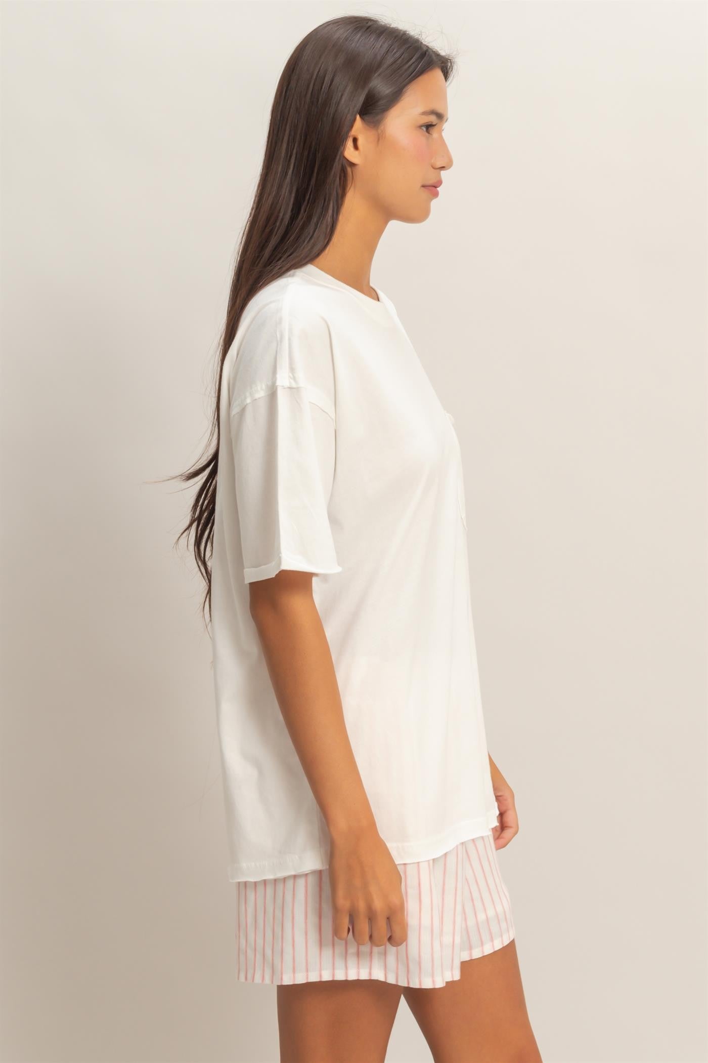 woman wearing a white oversized t-shirt with a crew neckline and light pink striped shorts