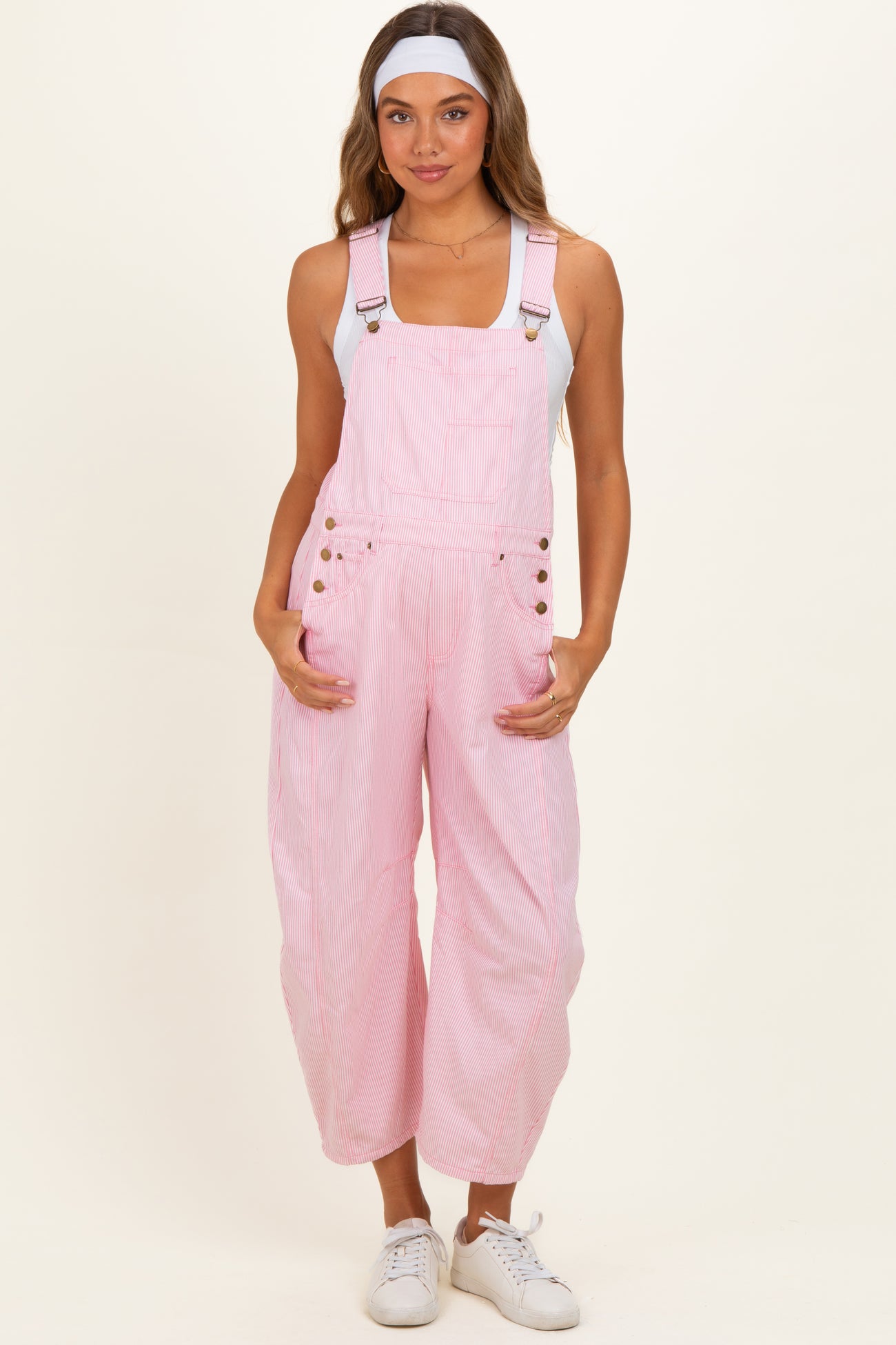 woman wearing a pink striped maternity overall with adjustable straps and front pockets