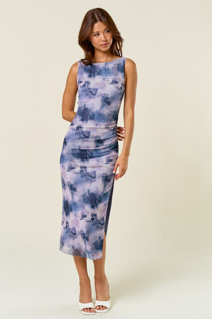 woman wearing a sleeveless purple and blue tie-dye midi dress with a form-fitting silhouette and side ruching